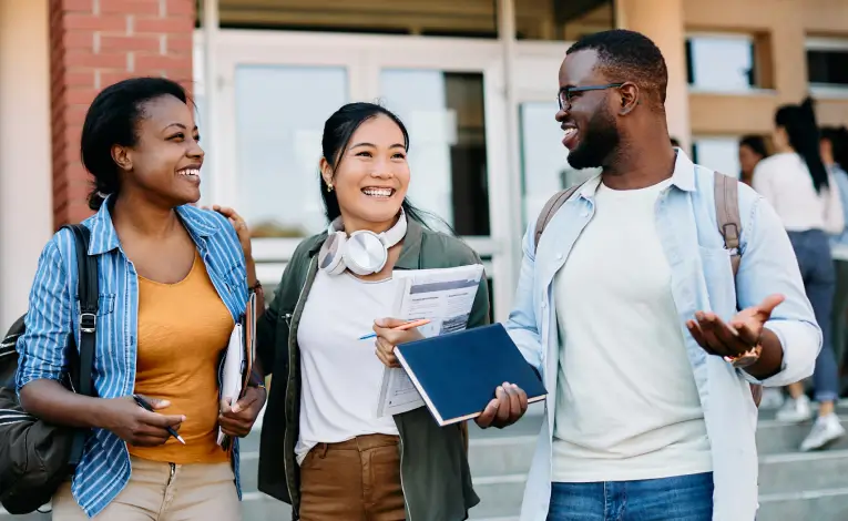 three young adults standing outside of a college building